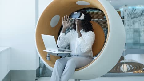 Focused-businesswoman-with-laptop-and-vr-headset